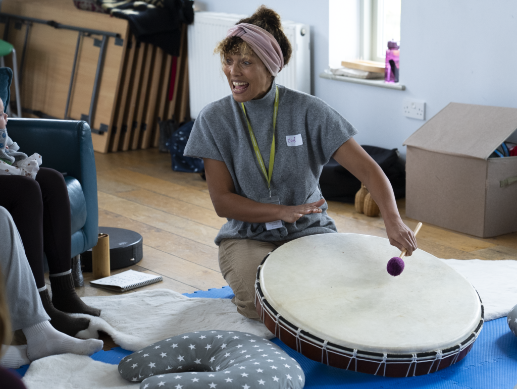 Zoë Palmer playing the drum in front of people at a music workshop